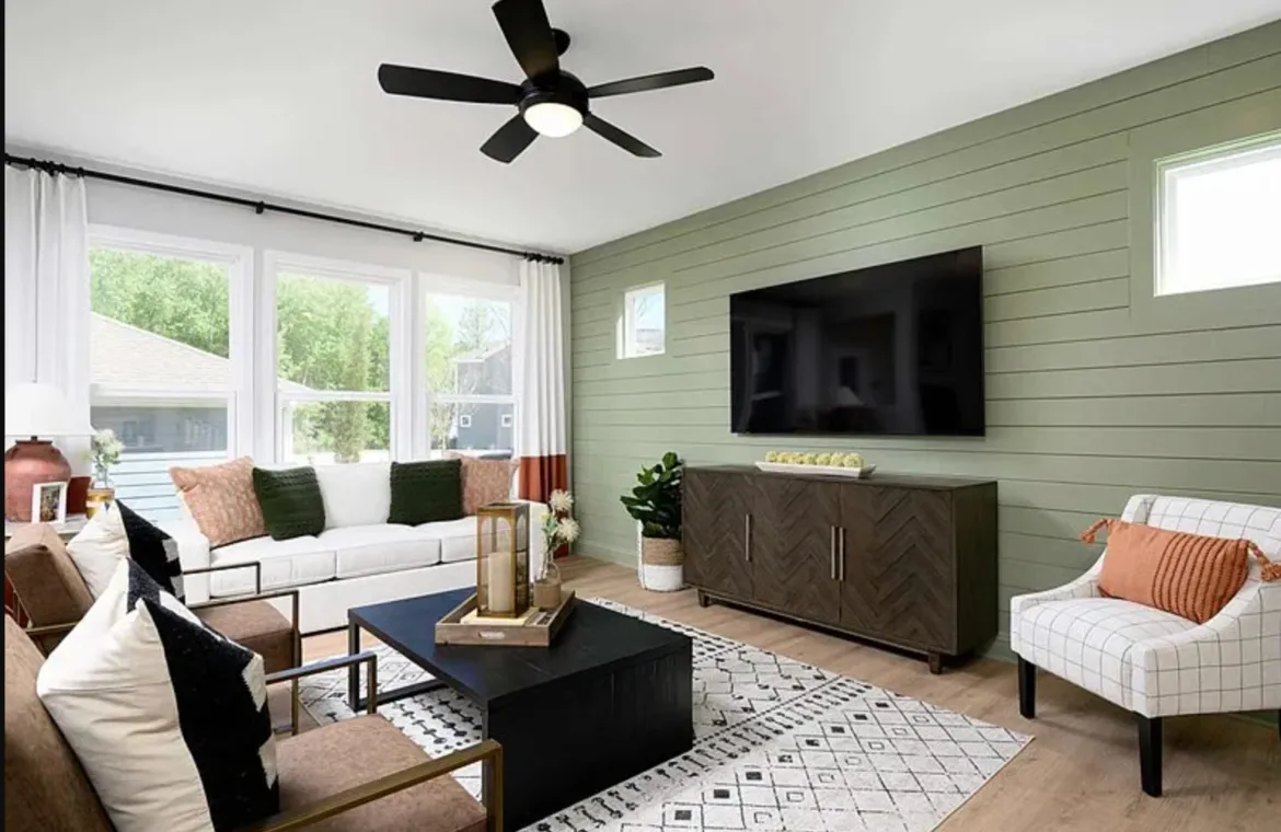 Living room with a sage green shiplap wall, wood sideboard, patterned rug, and white seating with terracotta pillows.