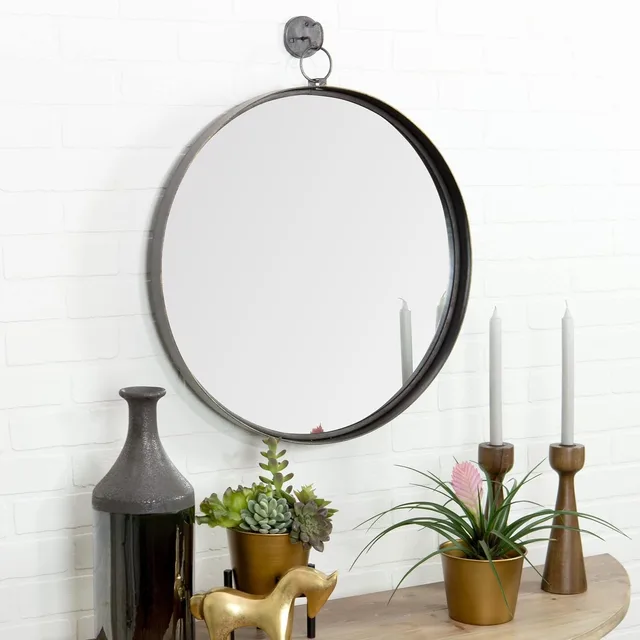 Round black-framed mirror hanging from a dark strap above a console.