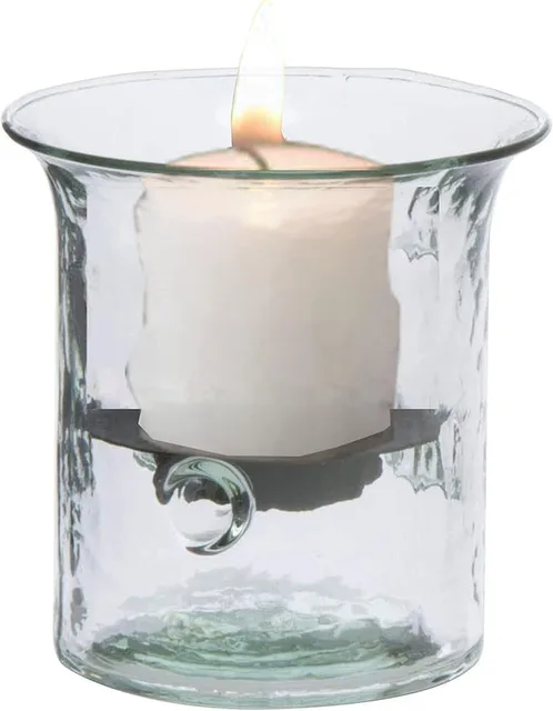Clear glass hurricane holding a lit white pillar candle on a metal insert.