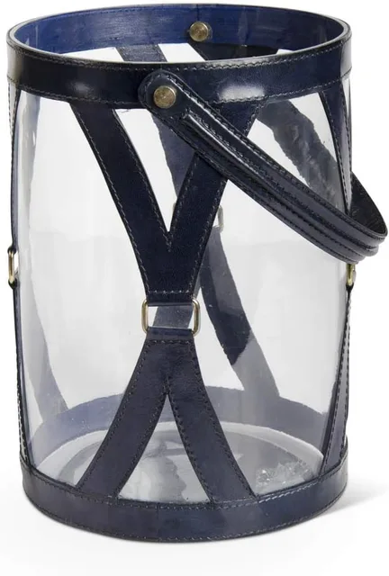Clear cylindrical glass lantern with dark blue leather straps and handle.