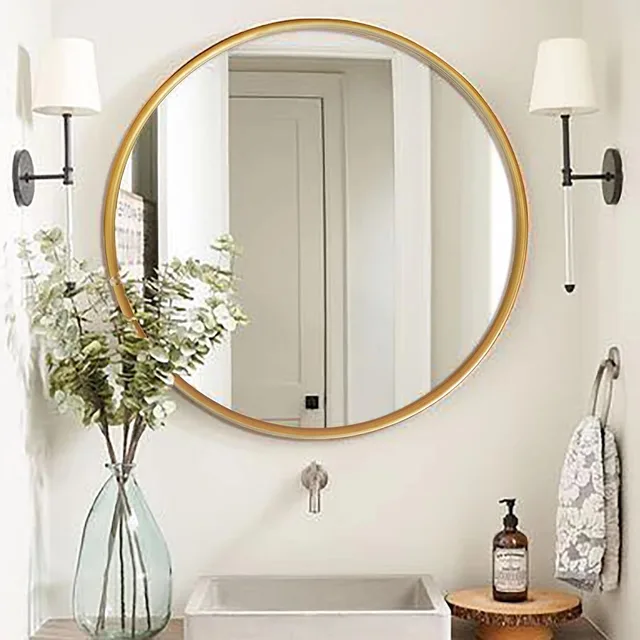 Round gold-framed mirror above a bathroom vanity between two wall lights.